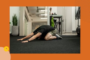 man wearing black shirt and green shorts doing child's pose back stretch at home