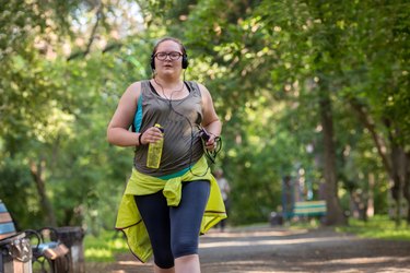Woman running through the park listening to music