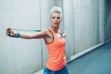 Modern sportswoman exercising with resistance band to increase bone density