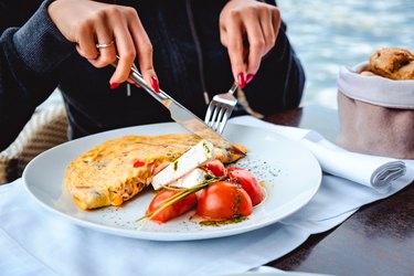 Woman eating high protein diet of scrambled eggs and cheese in restaurant