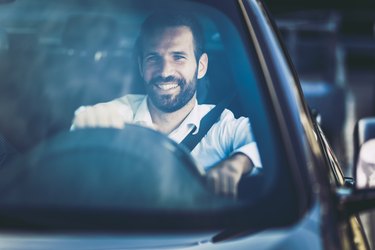 A smiling businessman driving his car on his commute to work
