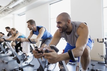 Smiling exerciser enjoying exercise class stationary bike gym