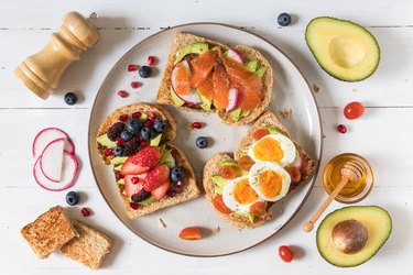 Assorted avocado toasts on white plate with ingredients on the side