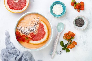Healthy breakfast set. Superfoods smoothie bowl with chia seeds, coconut, grapefruit and quince flowers. Overhead, top view, flat lay