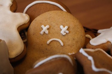 close view of a gingerbread cookie with a sad face drawn in white icing, to represent the holiday blues