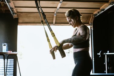 woman exercising with TRX suspension system in garage gym