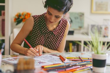 A woman coloring in an adult coloring book at home