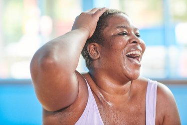 Close-up portrait of a woman at the gym laughing and doing fun exercises