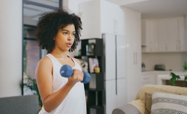 Person performing a dumbbell curl in living room.