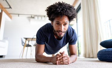 Person performing plank exercise with proper form at home in living room.