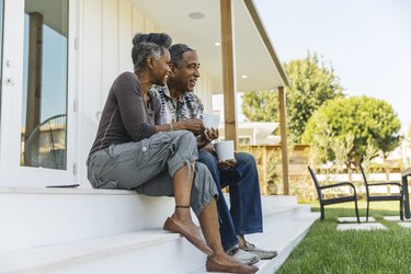 A couple drinking coffee outside on their porch, as an example of a morning habit to reduce inflammation