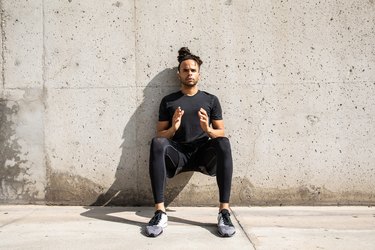 fit Black man doing a wall sit outdoors as part of a 5-minute leg workout