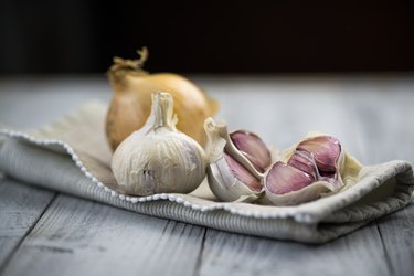Organic garlic and onion on wooden background, as a natural remedy for bug bite relief
