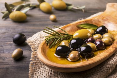 Healthy fat-rich olives with rosemary in the foreground