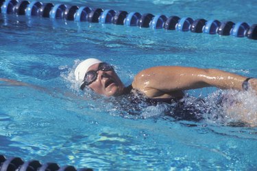 person wearing cap and goggles swimming laps in a pool