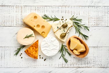 assortment of cheeses with camembert, blue cheese, parmesan, and brie on white wooden background