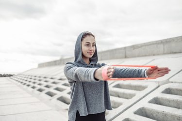Attractive fitness woman working out with fitness rubber bands outdoors