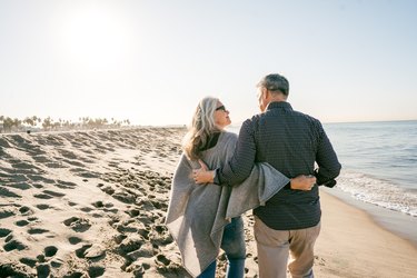 Back view of an older couple walking on the beach to lower inflammation