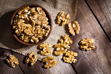 Organic omega-3-rich walnuts in bowl and scattered on wooden table