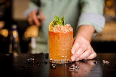 Bartender hand serving orange flavored vodka cocktail