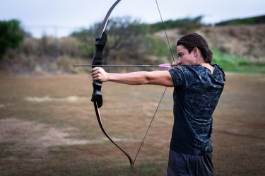 Archer aiming at his target at a shooting range outside.