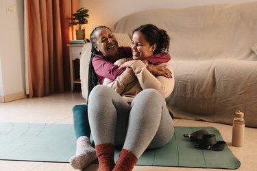 A mother and daughter smiling and embracing while exercising at home together, as an example of how to cope with cardiac anxiety