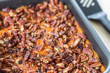 Sweet potato puff with pecans in a silver baking dish.
