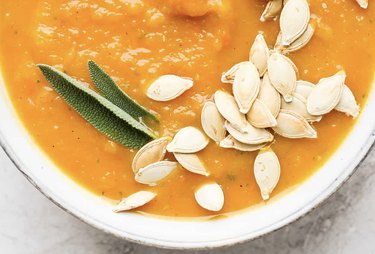 A close up of Pumpkin Soup with pumpkin seeds and bay leaves on top